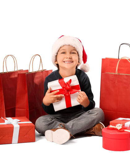 市场戴着圣诞帽的可爱小男孩 带着礼品盒和购物袋礼物可爱聚会