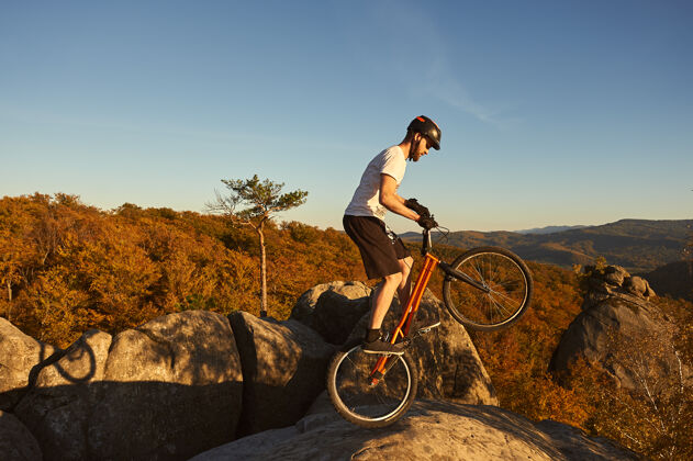 头盔在日落时分 职业自行车手在试骑自行车上保持平衡山地车集中杂技演员