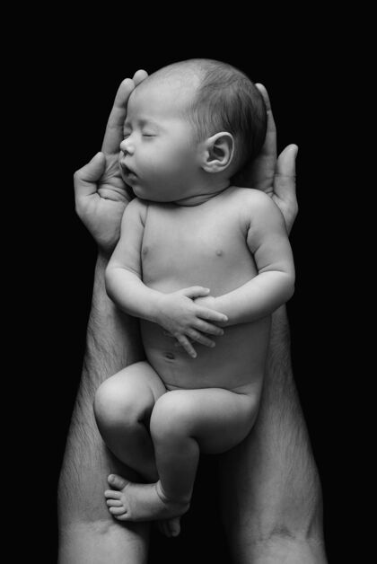 爱可爱的新生婴儿在爸爸的手上黑墙为人父母男性手
