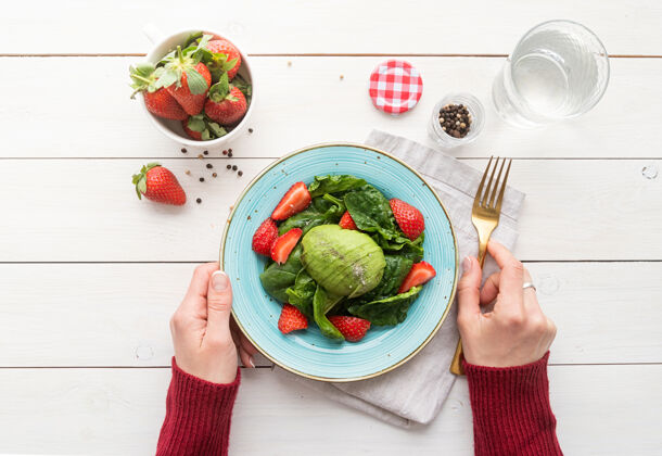 早餐健康饮食草莓沙拉 鳄梨 菠菜在白色木制背景上俯视平面午餐手开胃菜