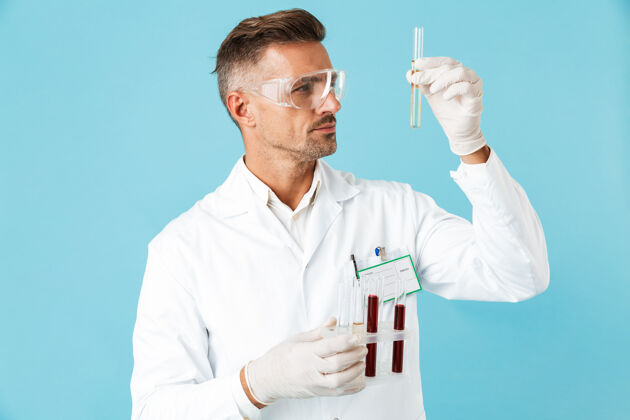 医疗医学专业人员戴着眼镜拿着带血的试管 孤零零地站在蓝色的墙上中年测试东西