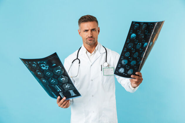 成人神经外科医生的肖像 30多岁 听诊器拿着x光片 孤立地站在蓝色的墙上听诊器医生从业者