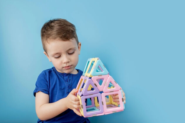 微笑男孩看了看颜色构造器的形状与磁铁的连接专注坐木头