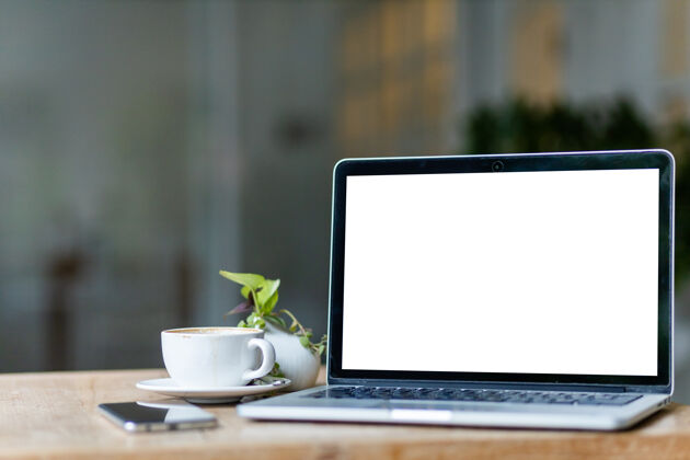 记事本模拟笔记本电脑与空屏幕咖啡杯和智能手机上的咖啡店背景 白色屏幕的桌子键盘显示器工作区