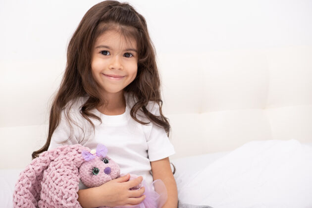 女孩穿着家装的小女孩和泰迪兔坐在家里的床上泰迪卧室护理