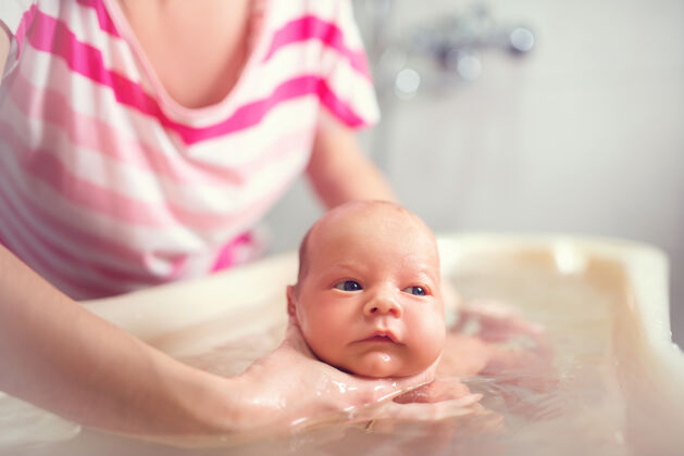 水细心的妈妈手里抱着一个漂亮有趣的小男孩湿身体护理