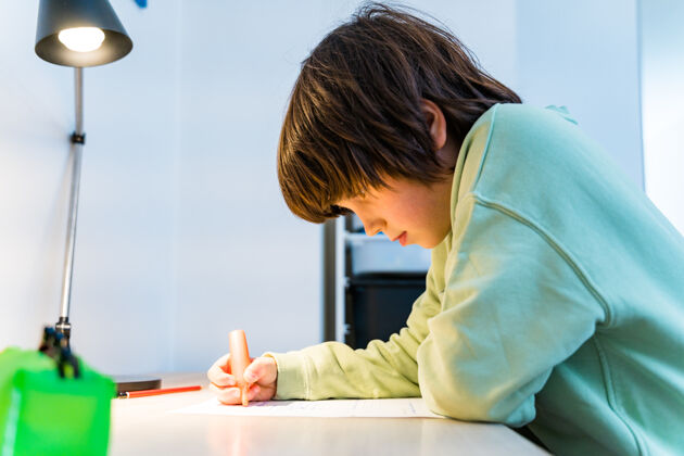 小学生小男孩坐在家里的桌子旁做作业钢笔铅笔房间