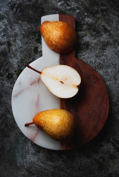 健康新鲜的土生土长的梨子放在半个大理石和木制砧板的乡村餐桌上顶视图平铺多汁秋季水果季节