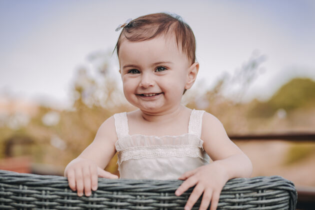 自然快乐的女婴坐在草椅上看着相机 微笑着可爱有趣年轻