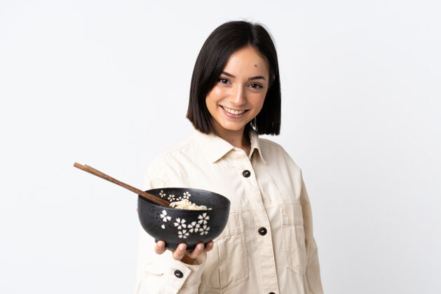 有趣一位年轻的白种女人 拿着筷子端着一碗面条 脸上洋溢着幸福的表情大笑黑发年轻