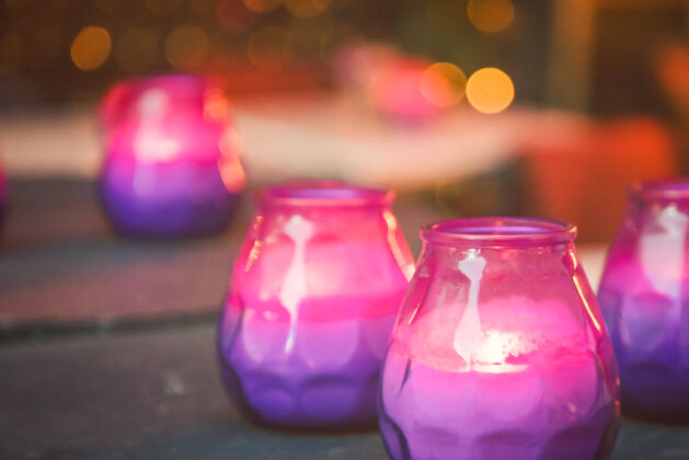 夜晚桌上亮着紫色和粉色的蜡烛灯光烛光灯光
