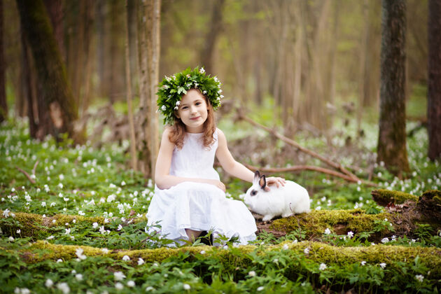 可爱美丽的小女孩穿着白色的连衣裙 在春天和白兔在一起伍德.复活节时间到了农场花园草