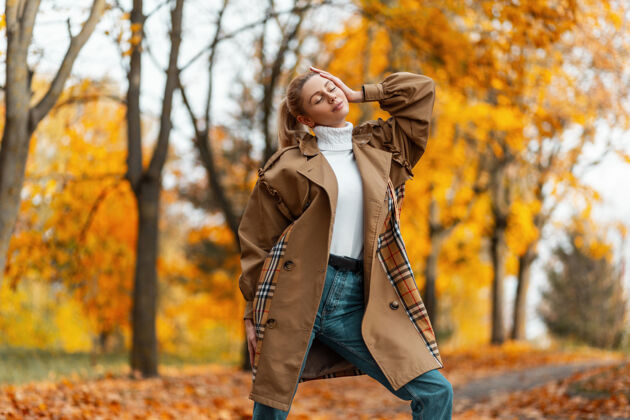 叶子一个穿着优雅外套的时髦发型的年轻女子在公园的户外摆姿势棕色美丽秋天