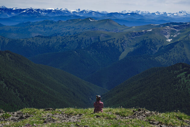 户外在阿尔泰共和国乌拉甘斯基地区 一位登山妇女在山顶上欣赏山脉的景色 俄罗斯流浪者旅程独自