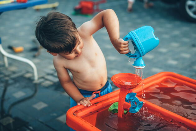 游戏一个没有穿衣服的白人男孩正在院子里玩塑料水玩具童年快乐庆祝