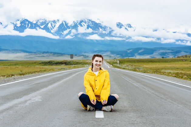 路快乐的女旅行者坐在路上 在山景里与她一起旅游度假自然女人年轻