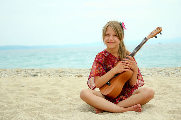 休闲海滩上可爱的小女孩带着四弦琴日光浴Ukelle夏威夷