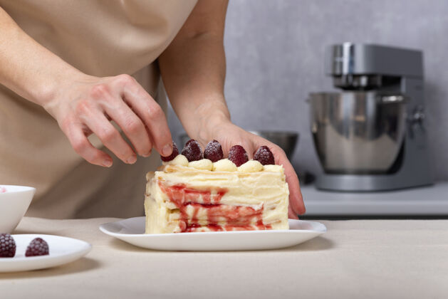 厨师糖果店的女人用糖果装饰蛋糕浆果 香草奶油蛋糕配浆果馅甜食手糕点厨师