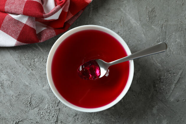 甜点在灰色纹理的桌子上放一碗红果冻的甜点概念风味樱桃冷