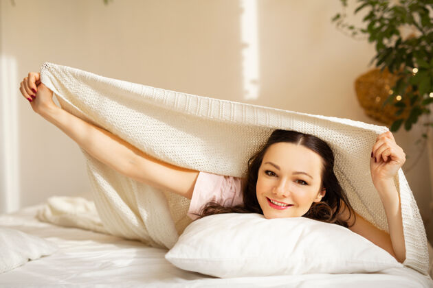 酒店卧室里漂亮的年轻女子躺在枕头上美丽肖像舒适