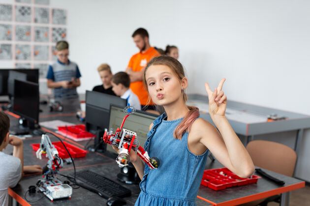 游戏机器人课上一个快乐的女学生的画像 她拿着一个由电脑上编程的塑料部件组装而成的机器人活动数码肖像