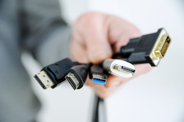 配件一个人手里有各种各样的电线和插头电子硬件插头