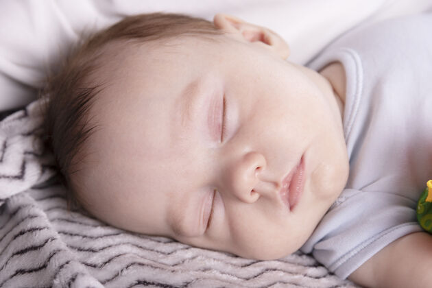 一可爱的宝宝在父母的床上舒舒服服地躺着睡觉躺着毯子男孩