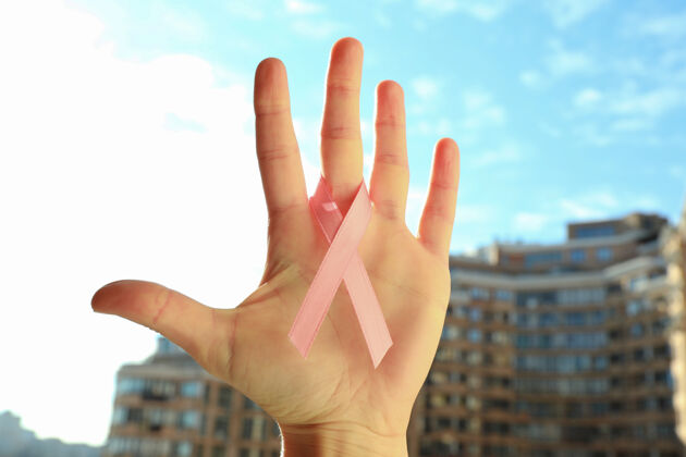 女性女性手拿粉红丝带户外癌症护理天空
