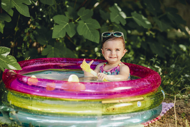 有趣快乐的宝宝拿着塑料勺 在苏美尔的游泳池里享受着她的一天玩具微笑阳光