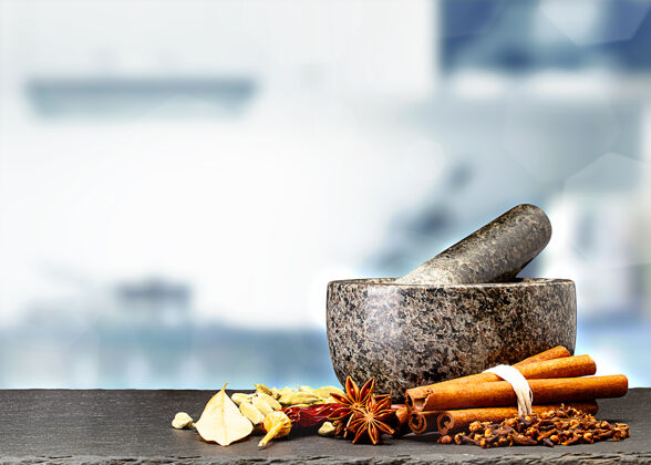 胡椒在模糊的厨房前面的桌子上放着花岗岩砂浆和香料分类研磨机杵