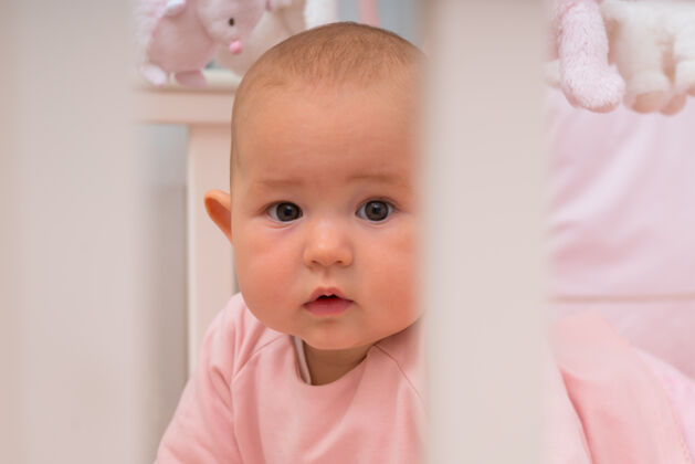 发展一个好奇的小女婴围着她的小床看着镜头 在一张特写照片里 她带着一种深思熟虑的表情凝视女性分娩