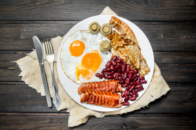 切片传统的英式早餐 有煎蛋 香肠和香肠豆子.on木制背景蘑菇早晨叉子