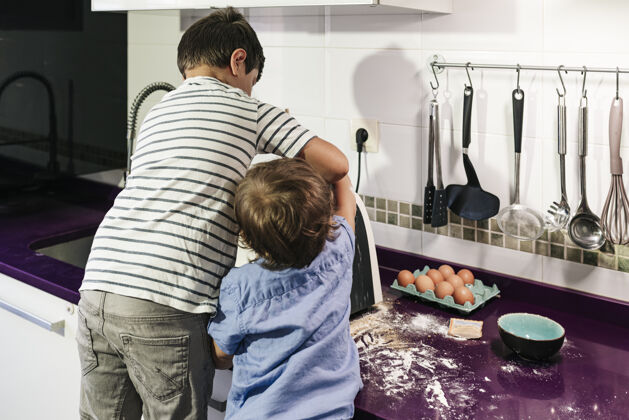 人两个孩子在用厨房机器人做煎饼成熟灯光两个