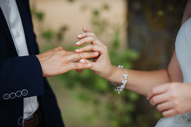 女人在婚礼那天 新娘把订婚戒指戴在新郎的手指上手白色结婚戒指