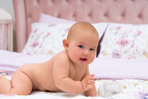 人年轻可爱的小宝宝爬在床上 从侧面看 看着相机信任内容裸露