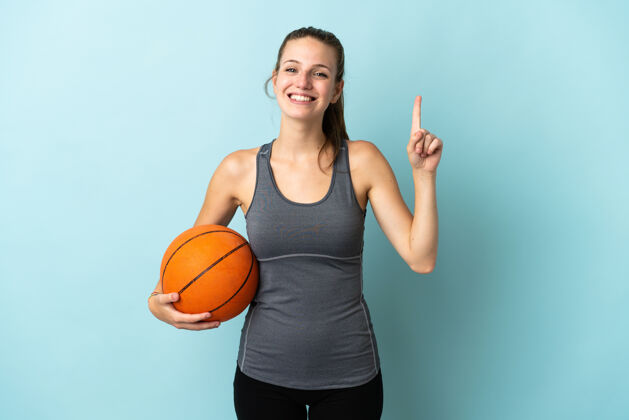 女人在蓝色背景上孤立地打篮球的年轻女子提出了一个好主意表情健身爱好