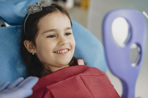 口腔儿童口腔科牙齿手术后 一个可爱的小女孩微笑着照镜子的特写镜头孩子女性椅子