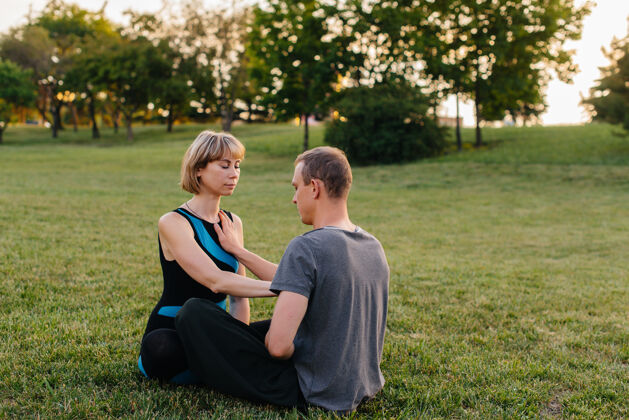 活动日落时分 一群人在公园里进行成对的瑜伽练习放松工作坊私人教练