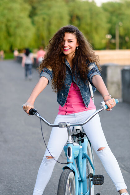 休闲美丽的年轻女孩穿着休闲服 在夏日的城市河堤边休息和骑自行车女孩城市欢乐