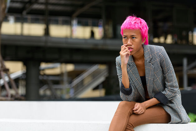 20多岁年轻叛逆的亚洲女商人的画像 粉红色的头发 在城市街道户外思考态度道路