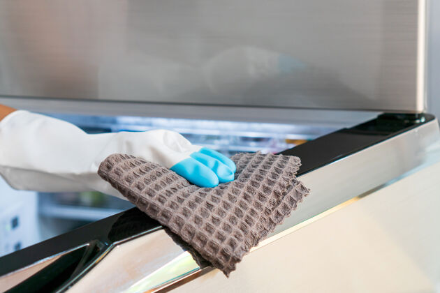 打开家庭主妇手戴橡胶手套 用超细纤维布清洁家中厨房的冰箱表面人家庭主妇架子