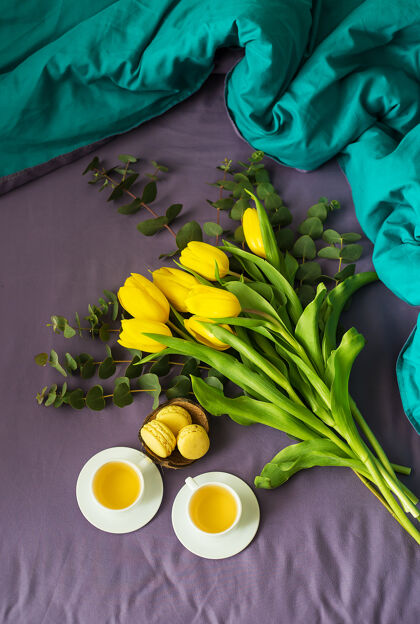 放松黄色郁金香 麦卡龙和两杯茶在床上自然白天花瓶