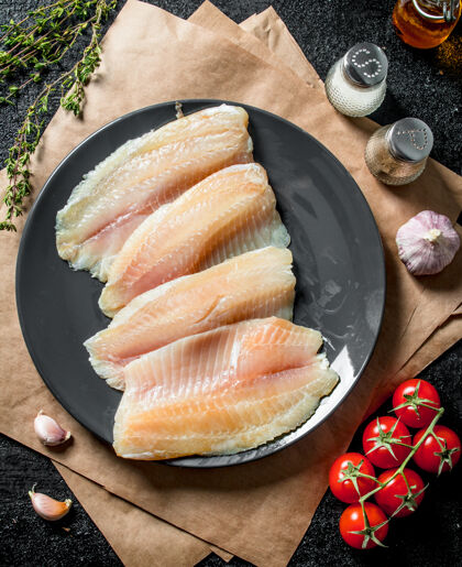 自然把罗非鱼鱼片放在盘子里 用纸 香料 百里香和西红柿健康新鲜物品