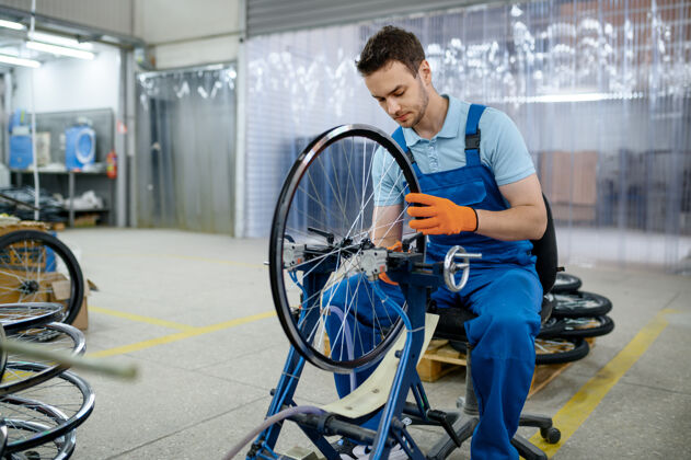 公机床上的男工人正在检查自行车的轮辋工厂自行车车轮在车间装配安装轮辋机械