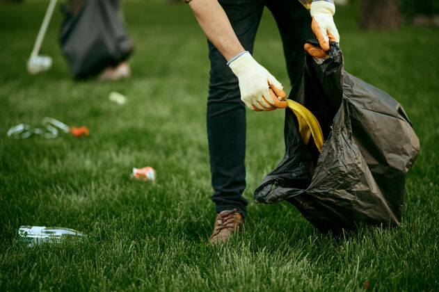 生态系统年轻人在公园里用袋子收集垃圾 志愿服务男人清林 生态修复 生态生活方式 垃圾收集回收 生态关怀污染手套垃圾