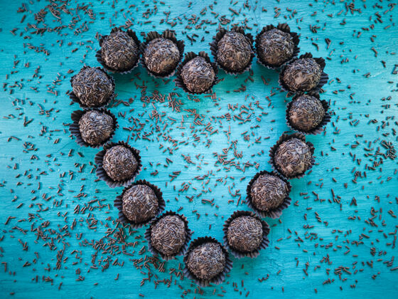 巧克力松露传统的巴西甜布里加迪罗在蓝色的桌子上形成心形糖果颗粒甜点