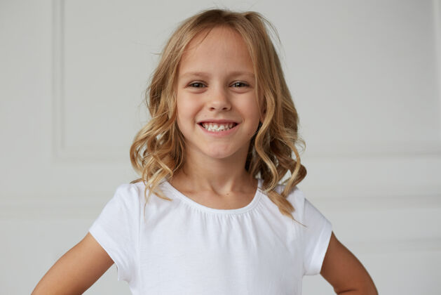 姿势一个可爱的微笑的小女孩展示她的牙齿嚼口香糖的特写镜头年轻小金发