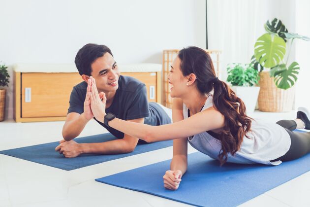 运动装亚洲年轻夫妇在家一起锻炼情侣男性瑜伽