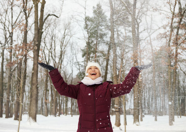 享受快乐的年轻女子在寒假玩雪 把洁白的 松软的雪扔进雪里享受空气霜冻冬日休闲活动寒冷
