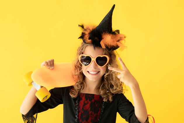 恐怖身着女巫服装的美丽女孩的画像映衬在黄色的表面上女巫十月青少年